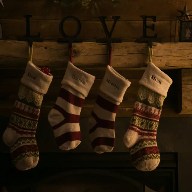 Four knitted Christmas stockings hanging from a wooden mantel