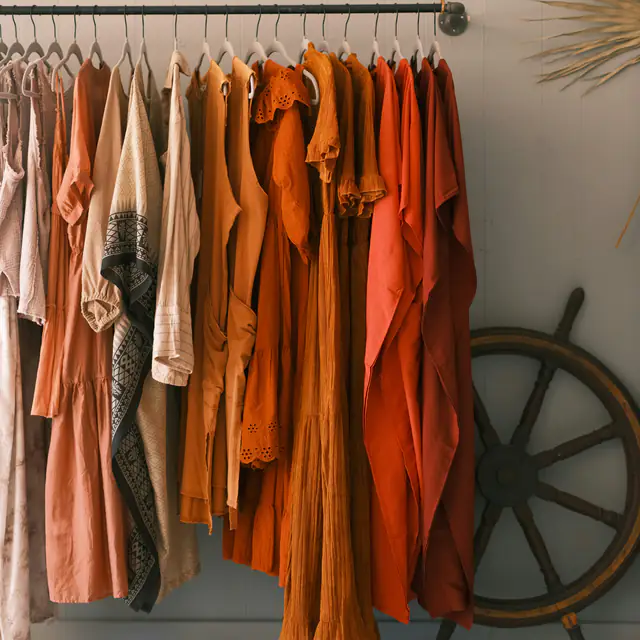 Linen dresses and shirts in rust, ochre and cream hanging on a clothes rail