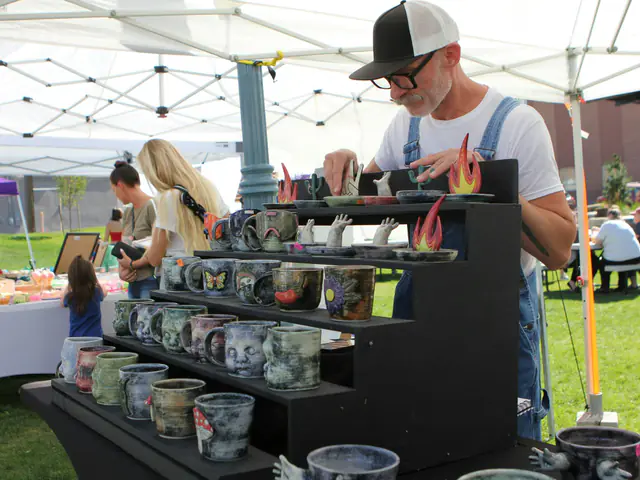 A potter arranging his handmade mugs on a stand at an outdoor market stall
