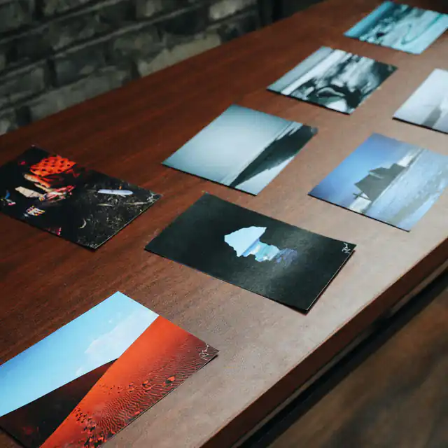Photographic prints of landscapes and seascapes laid out on a long wooden table