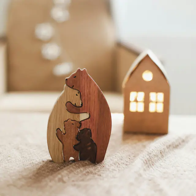 A carved wooden bear family puzzle beside a small wooden house night light