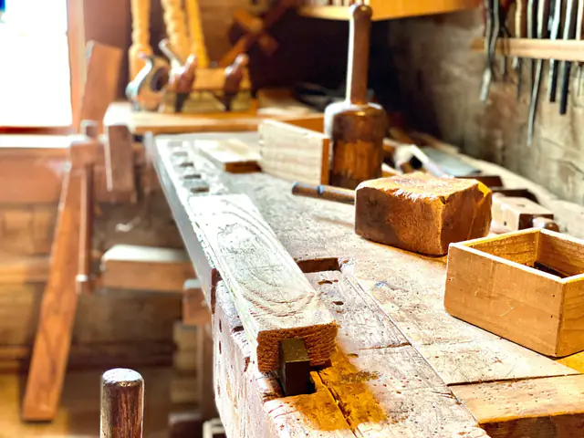 A worn woodworking bench with a mallet, wood blocks and a small wooden box in soft light